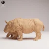 Les deux figurines de la maquette rhinocéros adulte et bébé posées sur un plan de travail en bois de modéliste, à côté d'un pinceau fin, attendant de recevoir leurs premières couches de couleurs.