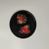 524a2ef0-764b-4259-88ab-e29930f3f94d Plat en résine époxy de forme ronde avec motifs de roses rouges et de feuilles vertes, parfait pour servir des petits objets.