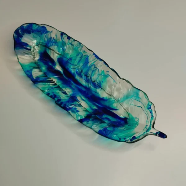 637e5e29-0822-4b4a-8759-37f7f0f093e2 Vide-poche en forme de feuille avec couleurs turquoise et bleu foncé, parfait pour ranger des petits objets.