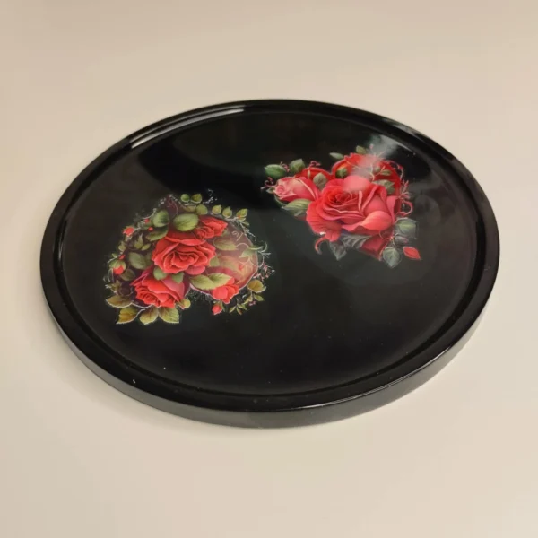 66a99b16-8162-4fe4-bd55-9f4af38f2091 Plat en résine époxy de forme ronde avec motifs de roses rouges et de feuilles vertes, parfait pour servir des petits objets.