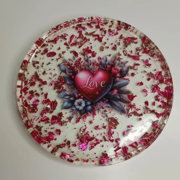 Vide-poche en résine époxy de forme ronde avec un cœur au centre, entouré de paillettes roses et de fleurs en résine, parfait pour ranger des petits objets.