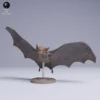 Figurine de chauve-souris en plein vol vue de face, prête à être peinte pour un diorama, montrant les détails fins de sa tête et de son pelage.