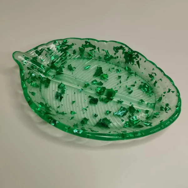 Vue rapprochée sur les nervures finement sculptées de la coupelle en résine époxy, montrant les éclats brillants des paillettes vertes sous la lumière.