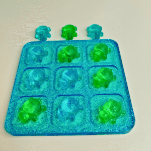 Jeu de morpion en résine époxy avec pions tortues vertes et bleues, plateau transparent pailleté.