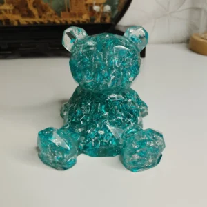 Ourson en résine époxy turquoise, texture cristalline, position assise.