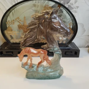 Sculpture en résine époxy représentant une tête de cheval stylisée avec un poulain, base verte texturée, décoration intérieure moderne.