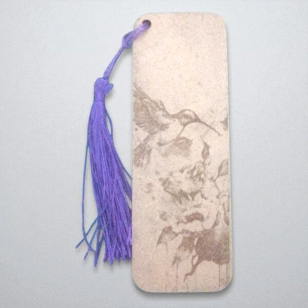 marque page oiseau qui butine-Photoroom (2) Marque-page en HDF gravé d'un colibri en vol, ficelle violette, tons beiges marbrés, design élégant.