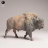 Vue de profil d'une figurine bison en résine non peinte, montrant sa posture de marche dynamique et la musculature détaillée de l'animal, idéale pour les projets de modélisme.