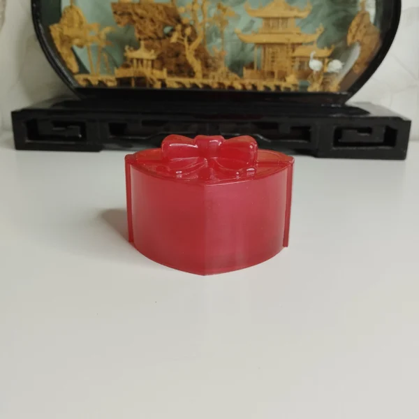 rangement-bagues-ouvert-decoratif La petite boîte décorative nacrée ouverte, révélant un intérieur lisse et doux où sont rangées plusieurs bagues dorées et une paire de boucles d'oreilles.