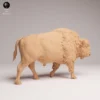 Figurine de bison miniature de 120 millimètres de long placée sur un établi d'artisan avec des pinceaux et des pots de peinture en arrière-plan, illustrant parfaitement ses proportions pour un diorama naturel.