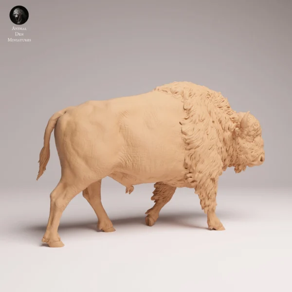 Figurine de bison miniature de 120 millimètres de long placée sur un établi d'artisan avec des pinceaux et des pots de peinture en arrière-plan, illustrant parfaitement ses proportions pour un diorama naturel.