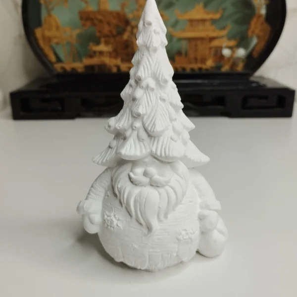 Un petit père Noël en résine blanche avec un sapin posé sur la tête, prêt à être peint avec des couleurs festives.