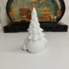 Gros plan sur le manteau finement texturé et le petit sapin de cette statuette de Noël artisanale.