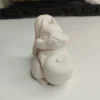 Une petite statuette écureuil en résine à peindre vue de face, montrant l'animal assis tenant un petit fruit rond.