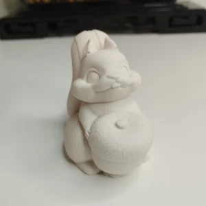 Une petite statuette écureuil en résine à peindre vue de face, montrant l'animal assis tenant un petit fruit rond.