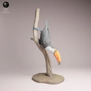 Profil d'une figurine toucan sur branche à peindre montrant les détails précis de son grand bec et la texture profonde de ses plumes.