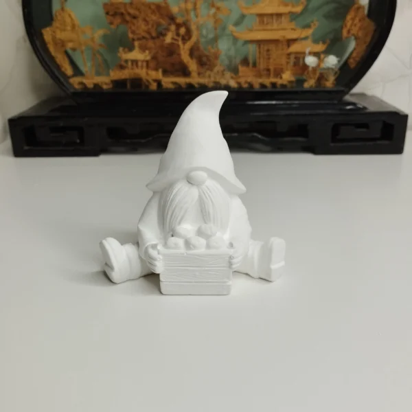 figurine-gnome-automne-peindre Gros plan sur les détails minutieux du panier en bois et des petites pommes sculptées, prêts à être personnalisés ou exposés au naturel sur une table d'automne.