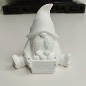 Notre gnome assis, vu de face, montrant son grand bonnet texturé et sa longue barbe, tenant tendrement son petit panier rempli de trois pommes.