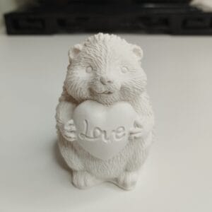 Statuette hérisson amoureux en résine acrylique blanc crème de 6,5 cm, tenant un cœur gravé "Love" sur un bureau.