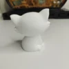Gros plan sur une décoration de bureau mignonne représentant un chat aux yeux expressifs, mettant en valeur la texture douce de la résine acrylique brute.