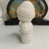 details-glacage-objet-deco-noel-gourmand Gros plan sur le ventre et le nœud papillon de la statuette en résine. La lumière met en évidence les petits boutons ronds sculptés et la douceur du matériau poncé à la main.