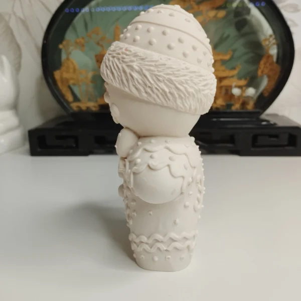 details-glacage-objet-deco-noel-gourmand Gros plan sur le ventre et le nœud papillon de la statuette en résine. La lumière met en évidence les petits boutons ronds sculptés et la douceur du matériau poncé à la main.