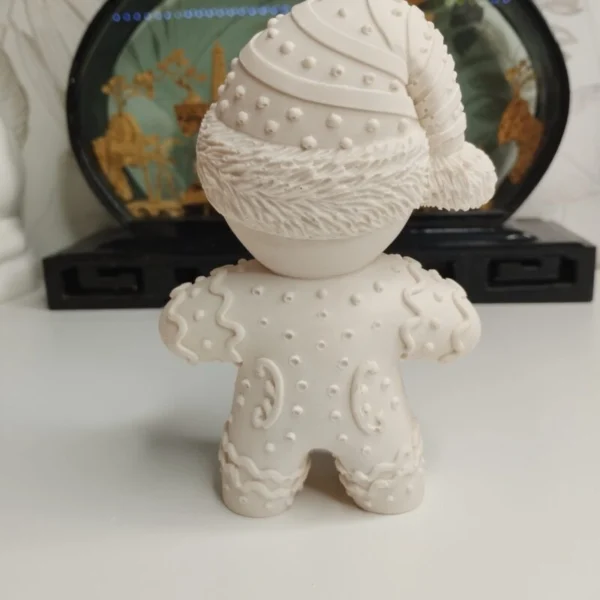 figurine-biscuit-noel-personnalisable-profil Vue de profil d'une décoration de Noël artisanale en résine représentant un biscuit festif. On aperçoit les détails en relief sur ses manches qui imitent un glaçage sucré en zigzag.