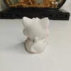 decoration-chat-minimaliste-ambiance Ambiance chaleureuse avec une figurine chat mignon intérieur placée sur une étagère à côté d'une petite plante verte et de quelques livres.
