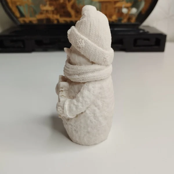 figurine-hivernale-texture-detail Profil de la décoration de Noël montrant la texture granuleuse de la résine acrylique, le relief du nez en carotte et l'aspect tricoté du bonnet.