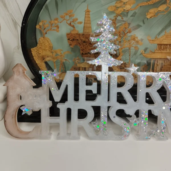 decoration-noel-moderne-paillettes-irisees Ambiance de fête chaleureuse avec le panneau de Noël artisanal en résine mis en valeur par la lumière douce de bougies LED en arrière-plan.