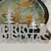 details-lettres-ajourees-paysage-hiver Gros plan sur les lettres ajourées et la silhouette d'un petit renne dans la forêt, captant la lumière avec des reflets bleutés et roses.