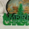 Décoration murale "Merry Christmas" en résine verte et pailletée, accrochée dans un intérieur scandinave