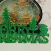 lettrage-vert-sapin-paillettes-details Gros plan sur la texture d'un lettrage merry christmas vert sapin, montrant les reflets irisés et la surface parfaitement lisse de la matière.