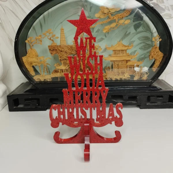 Lettres joyeux noël à poser d'une hauteur de 175 mm, en résine rouge vif scintillante, entourées de branches de sapin et de petites pommes de pin.