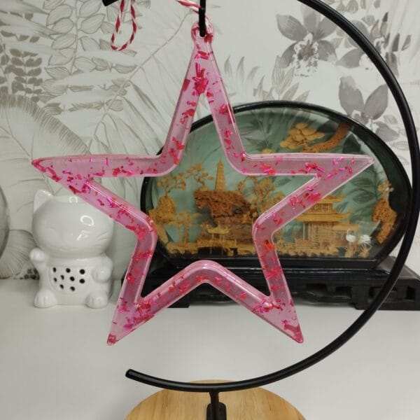 Étoile rose en résine transparente sur une étagère avec des décorations pastel