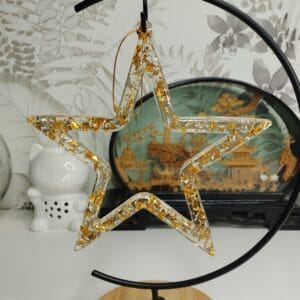 Ornement "Étoile Éclatante" dorée en résine transparente suspendu sur un sapin de Noël