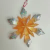 detail-artisanat-flocon-dore Gros plan sur les finitions d'un ornement flocon de neige scintillant, montrant le dégradé ambré de la résine lisse et la densité des paillettes irisées sur les extrémités.