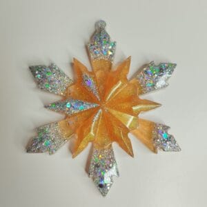 Flocon de neige en résine pailleté posé sur une table de Noël