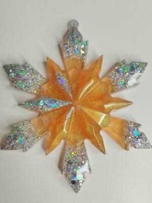 Flocon de neige en résine pailleté posé sur une table de Noël