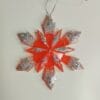 Ornement flocon de neige rouge pailleté en résine époxy suspendu sur un sapin de Noël décoré