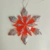 Ornement flocon de neige rouge pailleté en résine époxy suspendu sur un sapin de Noël décoré