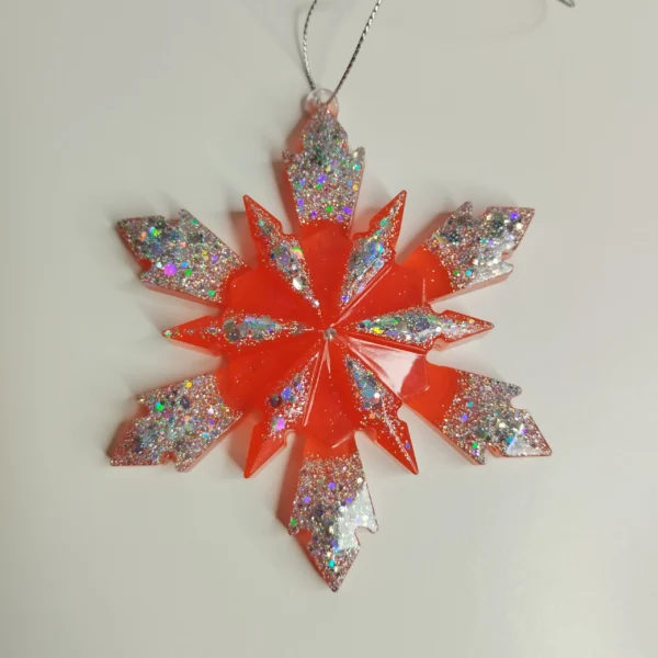 Ornement flocon de neige rouge pailleté en résine époxy suspendu sur un sapin de Noël décoré