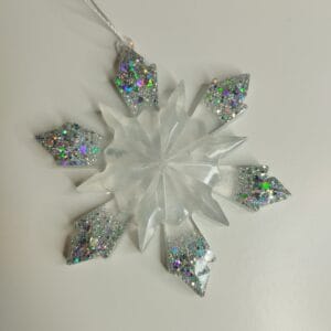 Ornement flocon de neige blanc nacré en résine époxy suspendu sur un sapin de Noël décoré