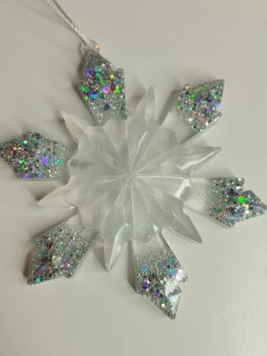 Ornement flocon de neige blanc nacré en résine époxy suspendu sur un sapin de Noël décoré