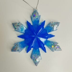 Flocon de neige bleu nuit posé sur une cheminée avec des guirlandes lumineuses bleues