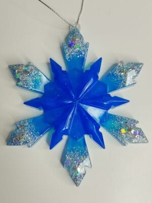 Flocon de neige bleu nuit posé sur une cheminée avec des guirlandes lumineuses bleues