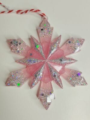 Gros plan sur les paillettes argentées et irisées de l'ornement flocon de sapin