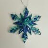 Ornement flocon de neige bleu glacier en résine époxy suspendu sur un sapin de Noël décoré