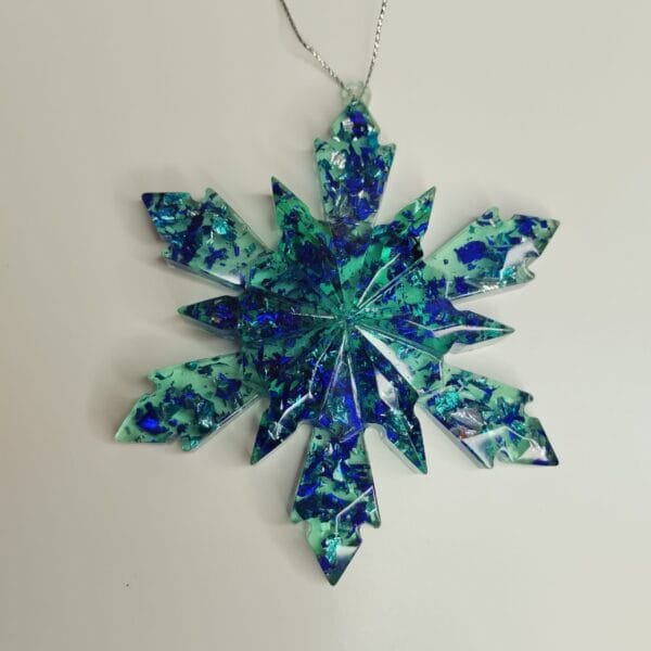 Ornement flocon de neige bleu glacier en résine époxy suspendu sur un sapin de Noël décoré