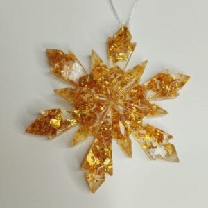 Ornement flocon de neige doré en résine époxy suspendu sur un sapin de Noël décoré